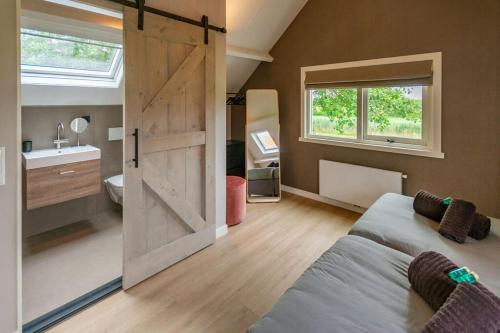 a bedroom with a sliding barn door and a bathroom at WaddenParels Zoet in Midsland