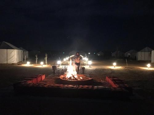 a man standing in front of a fire at night at Khadija Desert Camp in Merzouga