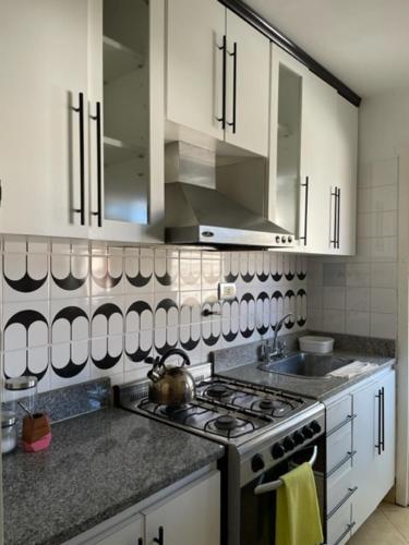 cocina con armarios blancos y fogones en Alquiler San Bernardo 2024 -Dpto 3 Amb en San Bernardo