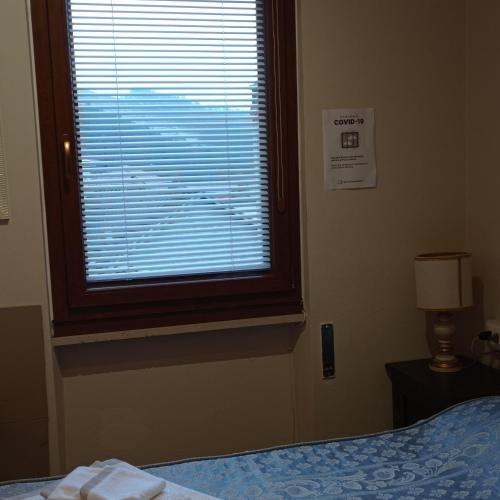 a bedroom with a window with a bed and a lamp at AL CORNIOLO in Zerba