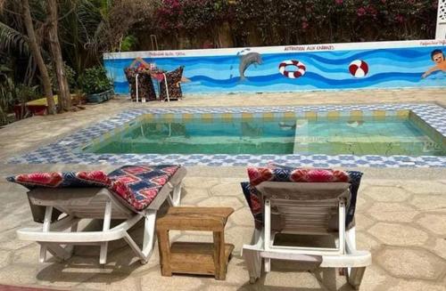 a swimming pool with two chairs and a table and a table and chairsitures at Auberge Africa Thiossane in Saly Portudal