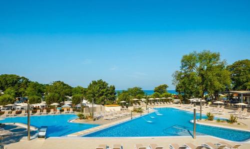 una piscina con sedie e ombrelloni in un resort di Easyatent Safari tent Aminess Maravea a Novigrad Istria