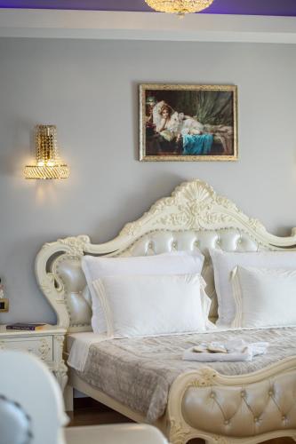 a bedroom with a white bed and a painting on the wall at Wellness Santa Hotel - adults plus12 in Agia Triada