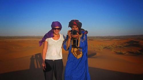 a man and a woman taking a picture in the desert at Khadija Desert Camp in Merzouga
