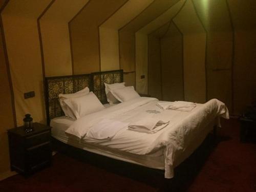 a bedroom with a bed with white sheets and pillows at Khadija Desert Camp in Merzouga