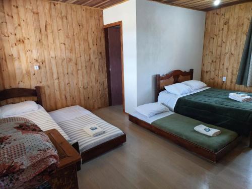 two beds in a room with wooden walls and wooden floors at Portal dos Cânions Pousada in Cambará