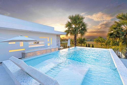 una piscina con 2 sillas y una casa en Palm Villa - Award Winning Modern Luxury & Exclusive Villa Resort, en Chiang Mai