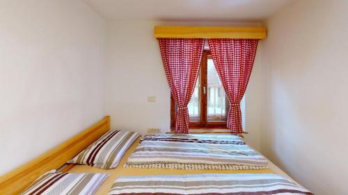 a bedroom with a bed with curtains and a window at hiša Margit, Rateče 150 in Rateče