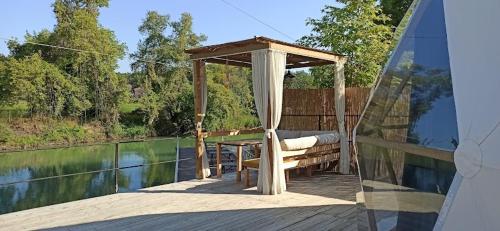 a wooden deck with a gazebo next to the water at Şelale Park Gizli Bahçe Glamping in Viransenir