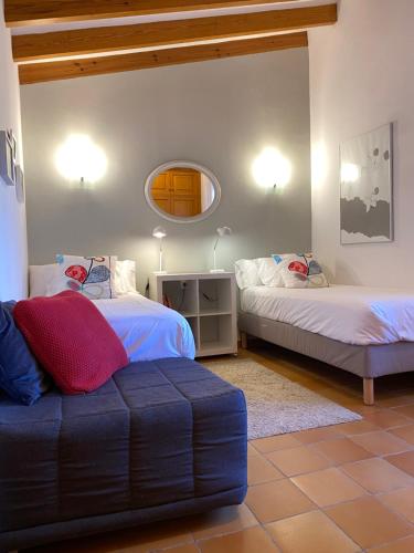 Zimmer mit 2 Betten, einem Sofa und einem Spiegel in der Unterkunft Sa Finqueta: Mansión única en el corazón de Sóller in Sóller