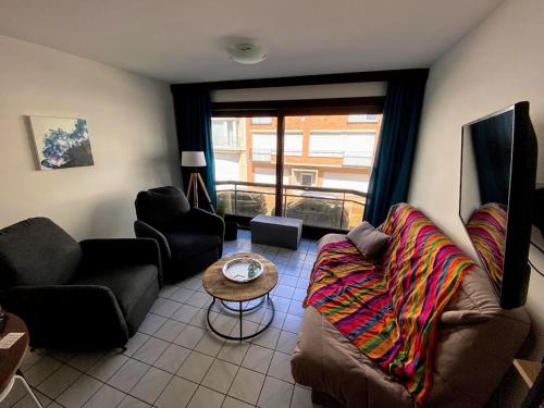 a living room with a couch and a table at Appart sympa 6p avec garage et terrasse ensoleillée et spacieuse à 25m de la Mer Westende in Middelkerke