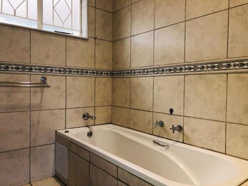 a white bath tub in a tiled bathroom at @ Home Bed & Breakfast in Brakpan