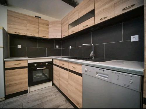 a kitchen with wooden cabinets and a sink and a dishwasher at Gite vomecourtois 