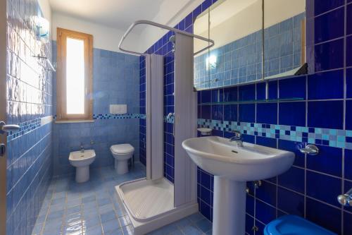 a blue tiled bathroom with a sink and a toilet at Appartamenti Marinelli - Santa Maria di Leuca in Leuca