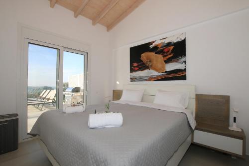 ein Schlafzimmer mit einem großen Bett und einem großen Fenster in der Unterkunft Sunset Sea View Villa 10 in Afionas