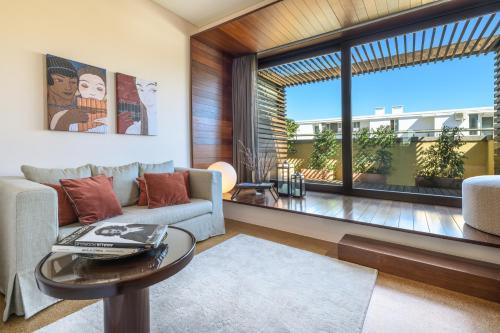 a living room with a couch and a table and a large window at Hotel Britania Art Deco - Lisbon Heritage Collection - Avenida in Lisbon