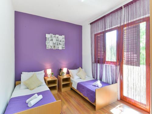 2 bedden in een kamer met paarse muren en een raam bij Holiday home Antonia with pool in Galovac