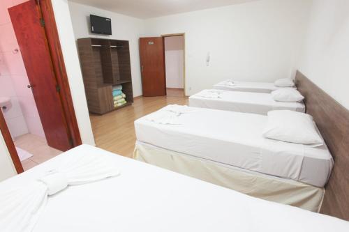 3 łóżka w pokoju z kominkiem w obiekcie Hotel Perez w mieście Pouso Alegre