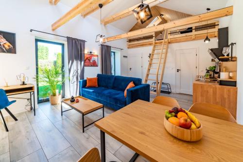 a living room with a blue couch and a table with fruit at Apartamenty Pod Dębami Stadnina Koni SPA Jezioro i Morze Sarbsk in Sarbsk