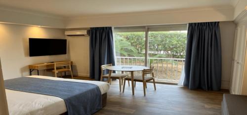 une chambre d'hôtel avec un lit, une table et une fenêtre dans l'établissement Résidence Carlton - Entièrement rénové, à Beaulieu-sur-Mer