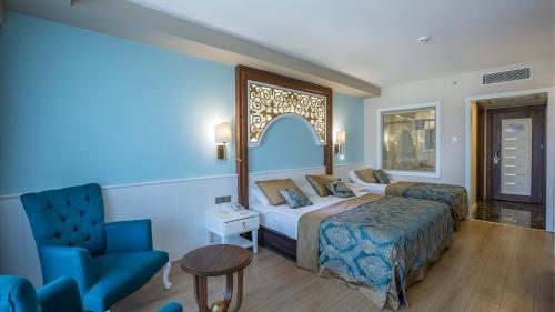une chambre d'hôtel avec un lit et une chaise dans l'établissement J'adore Deluxe Hotel & Spa Ultra All Inclusive, à Sidé
