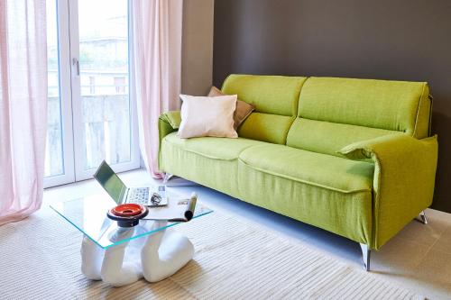 a living room with a green couch and a table with a laptop at GREEN RIBBON in Milan