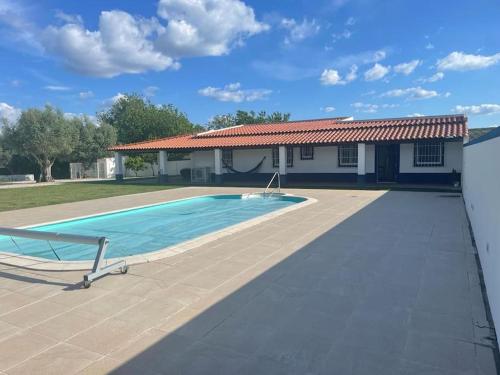 a swimming pool in front of a house at Casa das Oliveiras in Avis