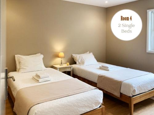 two beds in a room with a clock on the wall at Casa dos Pinheiros 109 - Private Villa with pool & heated SPA in Porto
