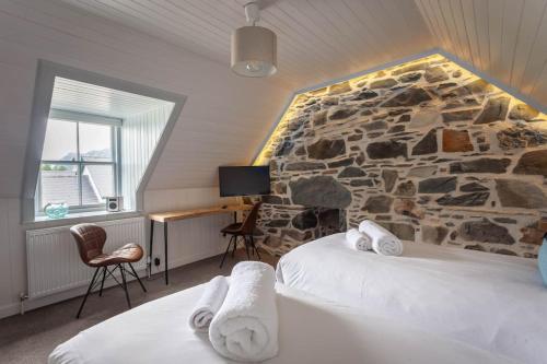 a room with two beds and a stone wall at Plockton Sea View Apartment in Plockton