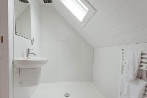 a white bathroom with a sink and a mirror at Plockton Sea View Apartment in Plockton