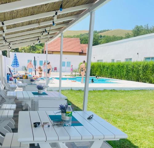 a patio with white tables and people in the pool at Blue Sky Transalpina in Săsciori