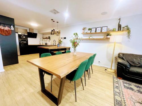 a living room with a wooden table and green chairs at Luxe Family Retreat! Pool, Sauna, Playground, Netflix, Disney Plus in Geraldton