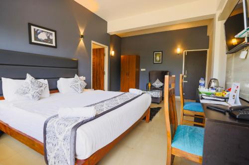 a bedroom with a bed and a desk with a computer at The Blossom Resort - Chikmagalur in Chikmagalūr