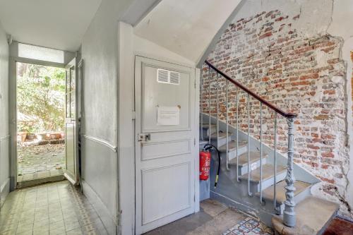 a hallway with a door and a brick wall at Aux Loges de L'orangerie in Versailles
