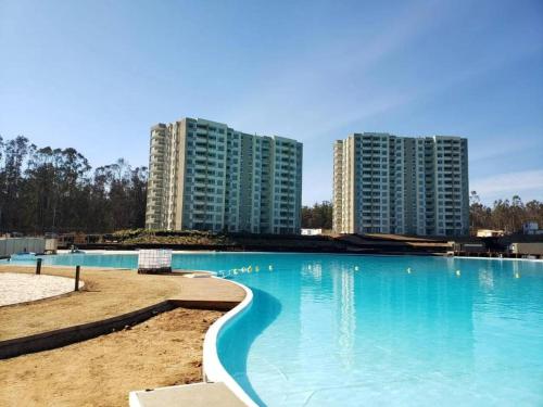 une grande piscine avec deux grands bâtiments en arrière-plan dans l'établissement Maravilloso Depto 2D2B en Condominio LagunaMar con Vista Hermosa a la Laguna Estacionamiento y Piscina, à Las Cruces