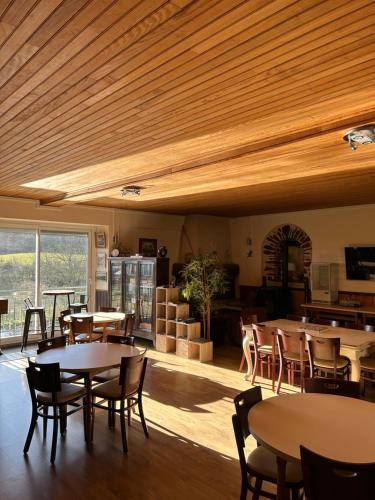 a dining room with tables and chairs and a large window at Hôtel l'Annexe in Moux-en-Morvan