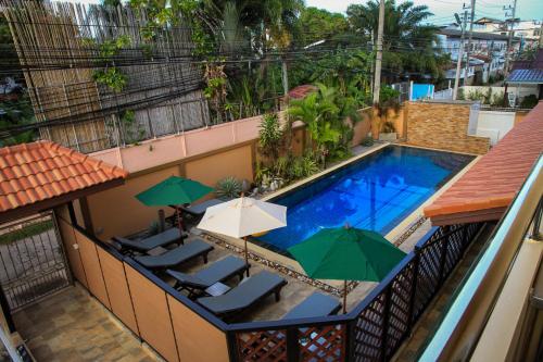 a swimming pool with chairs and umbrellas on a building at Sky Villa Hua Hin Guesthouse - Adults-Only in Hua Hin