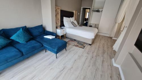 a living room with a blue couch and a bed at ARCHITECTS VIEW - EXECUTIVE SUITE in Durban