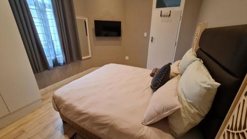 a bedroom with a bed with white sheets and pillows at ARCHITECTS VIEW - EXECUTIVE SUITE in Durban