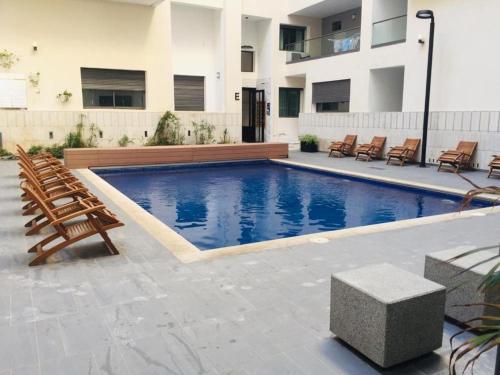 einen Pool mit Stühlen und ein Gebäude in der Unterkunft Miramare Cosy appartement pied dans l'eau avec piscine in Mohammedia