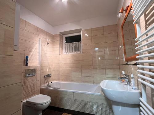 een badkamer met een bad, een toilet en een wastafel bij Apartamenty Beskidzkie in Ustroń