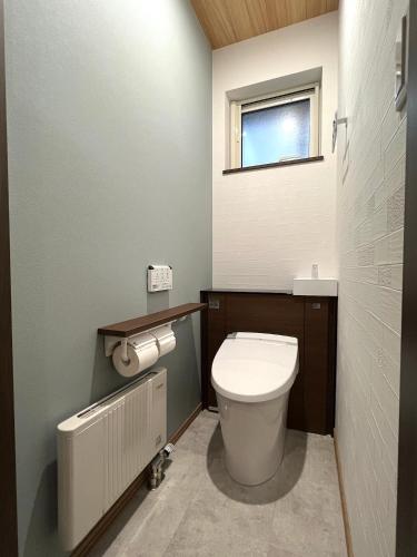 a small bathroom with a toilet and a window at Furano Yukisachi House in Furano