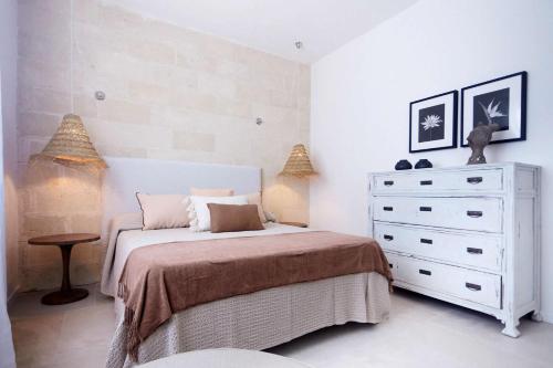 a bedroom with a white bed and a dresser at Villa Rocce Bianche in Favignana