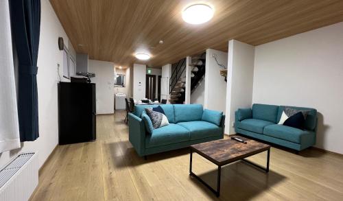 uma sala de estar com dois sofás azuis e uma mesa em Furano Yukisachi House em Furano