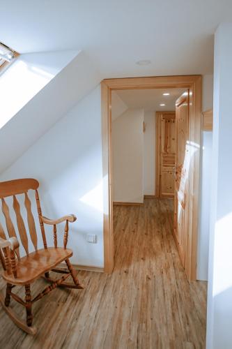 a wooden rocking chair in a hallway with a staircase at Apartments Čenda in Železniki