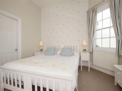 a white bedroom with a large white bed with blue pillows at The Boathouse in Seaview