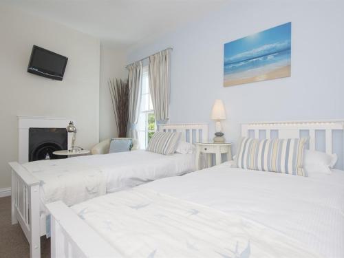 two white beds in a room with a fireplace at The Boat House - Isle of Wight in Seaview
