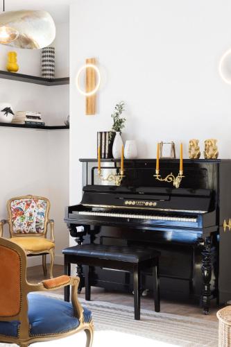 a black piano in a living room with chairs at Lugar do Ourives Boutique Hotel in Febres
