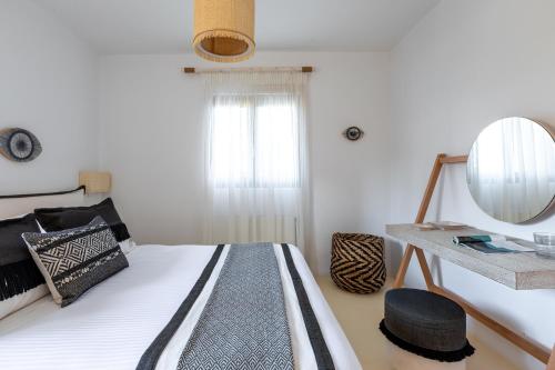 a bedroom with a bed with a mirror and a table at Amalgam Homes Paros in Ambelas