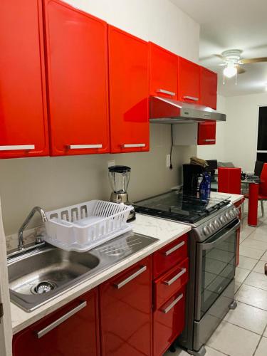 a kitchen with red cabinets and a dish rack on the counter at Departamento nuevo en Aldea Tulum, alberca e internet in Tulum